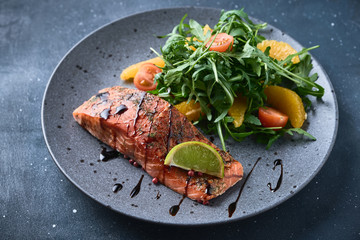 Hot smoked salmon with arugula salad, cherry tomato and orange. Healthy eating.