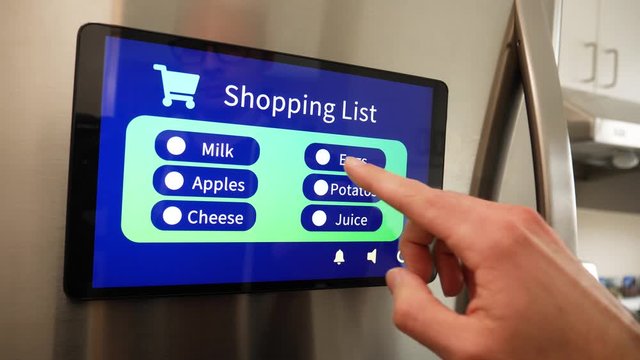 Man using Smart Refrigerator touch screen to make a grocery list for shopping for his Smart home in his kitchen