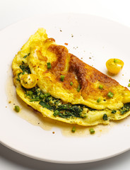 Omelet with spinach, green onions and cherry tomato on a white plate.
