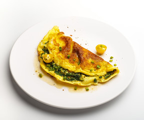 Omelet with spinach, green onions and cherry tomato on a white plate.