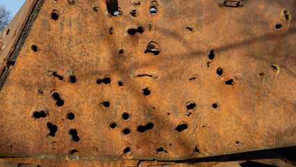 The armor of a tank pierced by bullets during the Great Patriotic War. Traces of war, rusty iron, wounds.