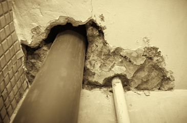 Residential apartment in a multi-storey residential building in the city. Replacing the old cast-iron sewer pipe with a plastic one. Black and white photography. Sepia.