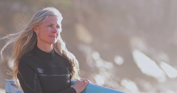 Close up senior beautiful woman holding surfboard at the beach