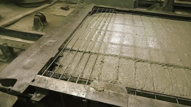A large radio-controlled machine fills the concrete in form. Workers in the workshop of the House-building plant. Industrial interior. Concrete plant.