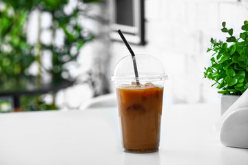 Cup of tasty iced coffee on table in cafe