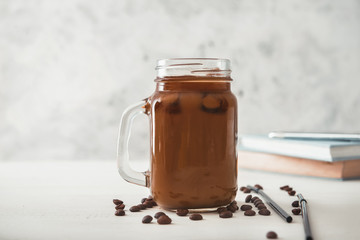 Mason jar of tasty iced coffee on table