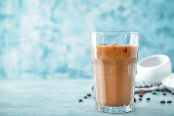 Glass of tasty iced coffee on color background