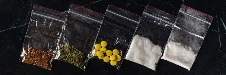 lethal concept: tobacco, weed, MDMA tablets, amphetamine crystals, heroin in plastic bags, on a...