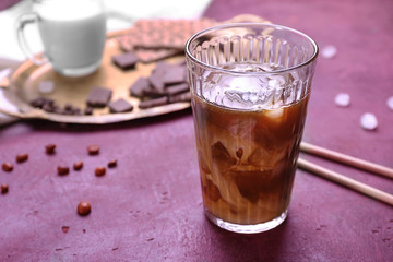 Glass of tasty iced coffee on color background