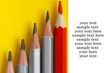 red pencil and gray pencils on a yellow paper background.Text