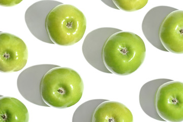 Top view on bright green apples and hard shadows on a white background