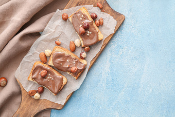 Fototapeta premium Board with fresh bread and chocolate paste on color background