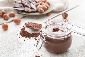 Jar with tasty chocolate paste on light background