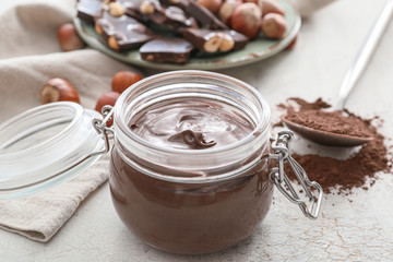Jar with tasty chocolate paste on light background