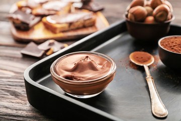 Bowl with tasty chocolate paste and hazelnuts on table