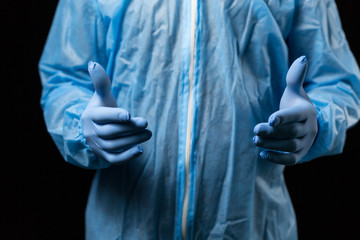 male hands in medical disposable gloves and chemical protective overalls, blue, close-up on a dark background