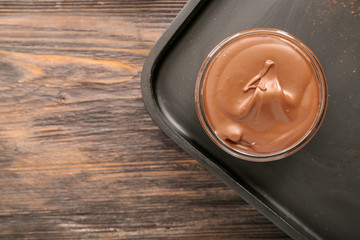Bowl with tasty chocolate paste and hazelnuts on table
