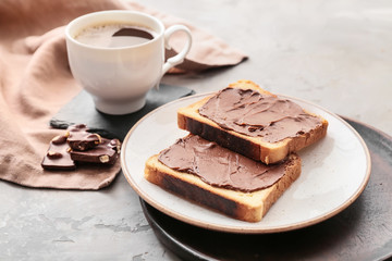 Plate with fresh bread, chocolate paste and cup of coffee on grunge background