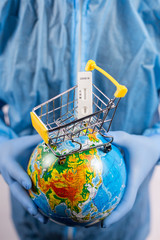 Hands in medical gloves holding a globe with a coronavirus test, online shopping during a pandemic, vertical frame, close-up with place for text