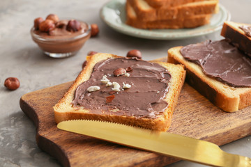 Fototapeta na wymiar Board with fresh bread and chocolate paste on grey background