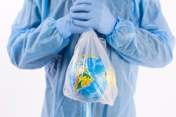 a man in a chemical protection suit and medical gloves holds a package in his hands with a planet inside, a pandemic in the hands of a man. Save the nature. close-up on a light background