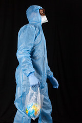 portrait of a man in a chemical protective suit, medical gloves, a mask and glasses holds a package with the planet Earth inside