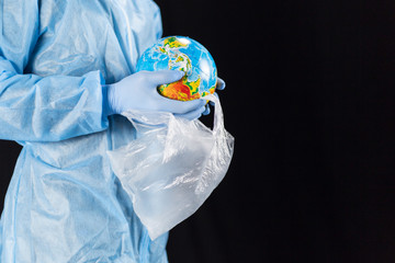 a man in a chemical protection suit and medical gloves holds a package in his hands with a planet, a pandemic in the hands of a man. Save the nature. close-up with place for text