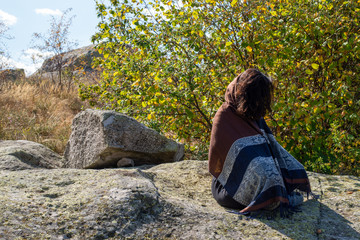 Young woman meditating at Belintash sacred place at the hear of the magical Rhodopes mountain.
