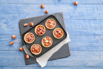 Tray with tartlets and tasty chocolate paste on table