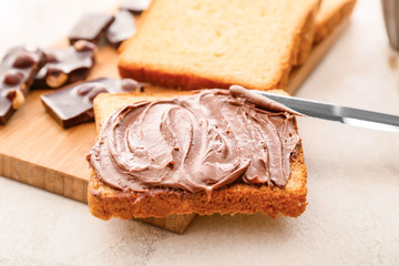 Board with fresh bread and chocolate paste on table