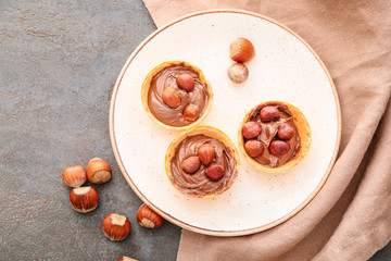Plate with tartlets and tasty chocolate paste on grey background