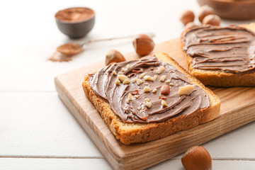 Fototapeta na wymiar Board with fresh bread and chocolate paste on table