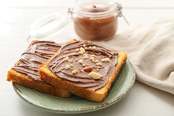 Plate with fresh bread and chocolate paste on table