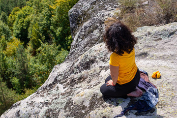 Naklejka na ściany i meble Girl meditating at the edge of a ancient sacred location.