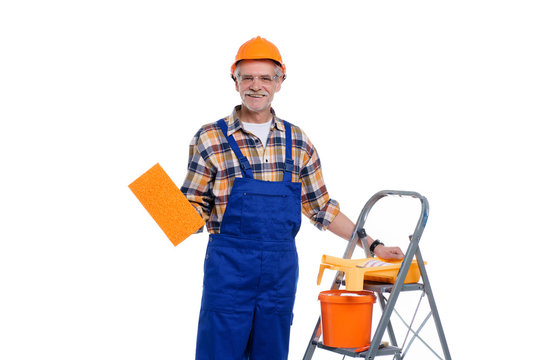 Repairs in the apartment, old man paint the walls with a paintbrush, looks at the camera and smiles stay on stepladder, isolated on white backround