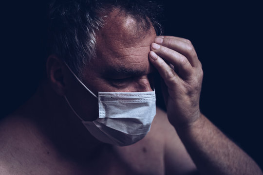 view of shirtless mature man touching face wearing surgical face mask