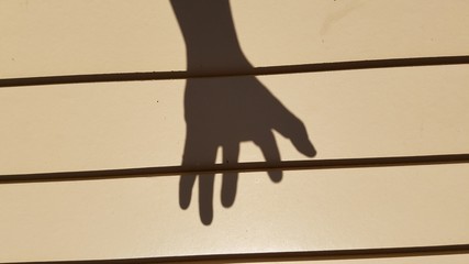 Hand gesture casting harsh shadow on the wooden wall