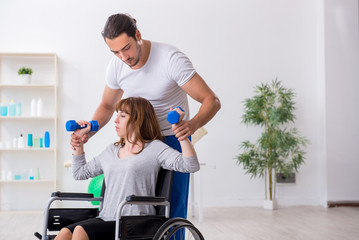 Woman in wheel-chair doing sport exercises with personal coach