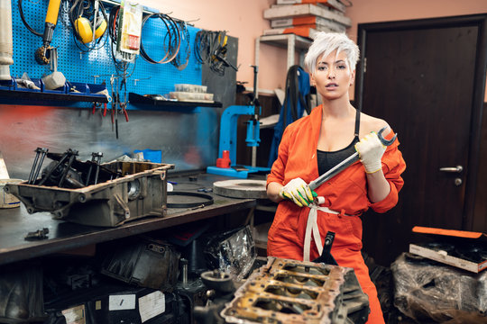 Sexy young woman repairing the car in a car service