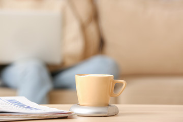 Cup of coffee with heater and newspaper on table