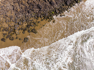Beach with waves and stones. View from above, with space in the sand. Holiday and vacation