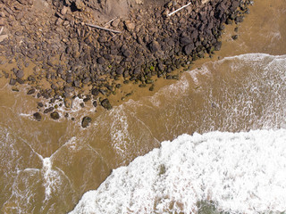 Beach with waves and stones. View from above, with space in the sand. Holiday and vacation
