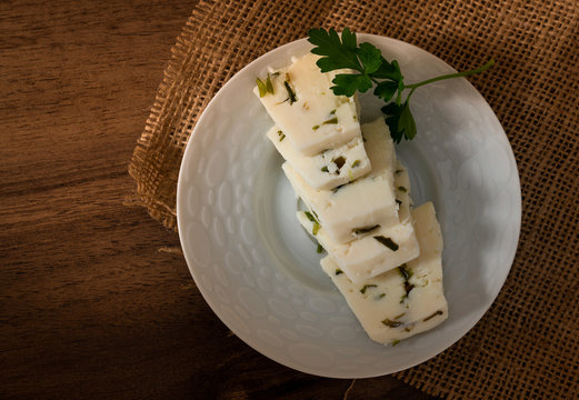 Sliced herby cheese served in a white plate
