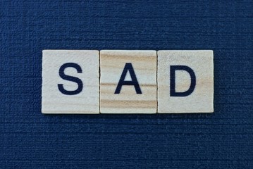 text from a gray short word sad of small wooden letters lies on a dark black table