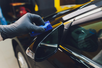Car detailing - Man applies nano protective coating to the car. Selective focus.