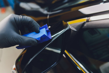 Car detailing - Man applies nano protective coating to the car. Selective focus.