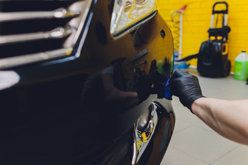 Car detailing - Man applies nano protective coating to the car. Selective focus.