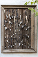 Vintage wooden panno with old cutlery on a white wall