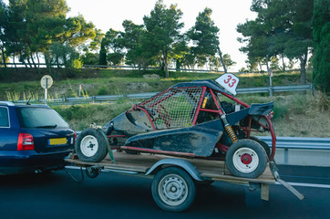 Car carrying trailer with an UTV off-road vehicle on highway road 