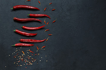 Red pepper pods, dried baby paprika and pepper peas on a black table top with spaces